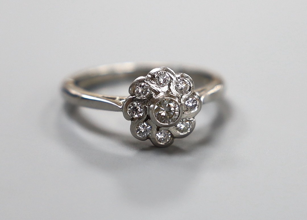 A modern platinum and collet set nine stone diamond flower head cluster ring, size O, gross weight 5.6 grams